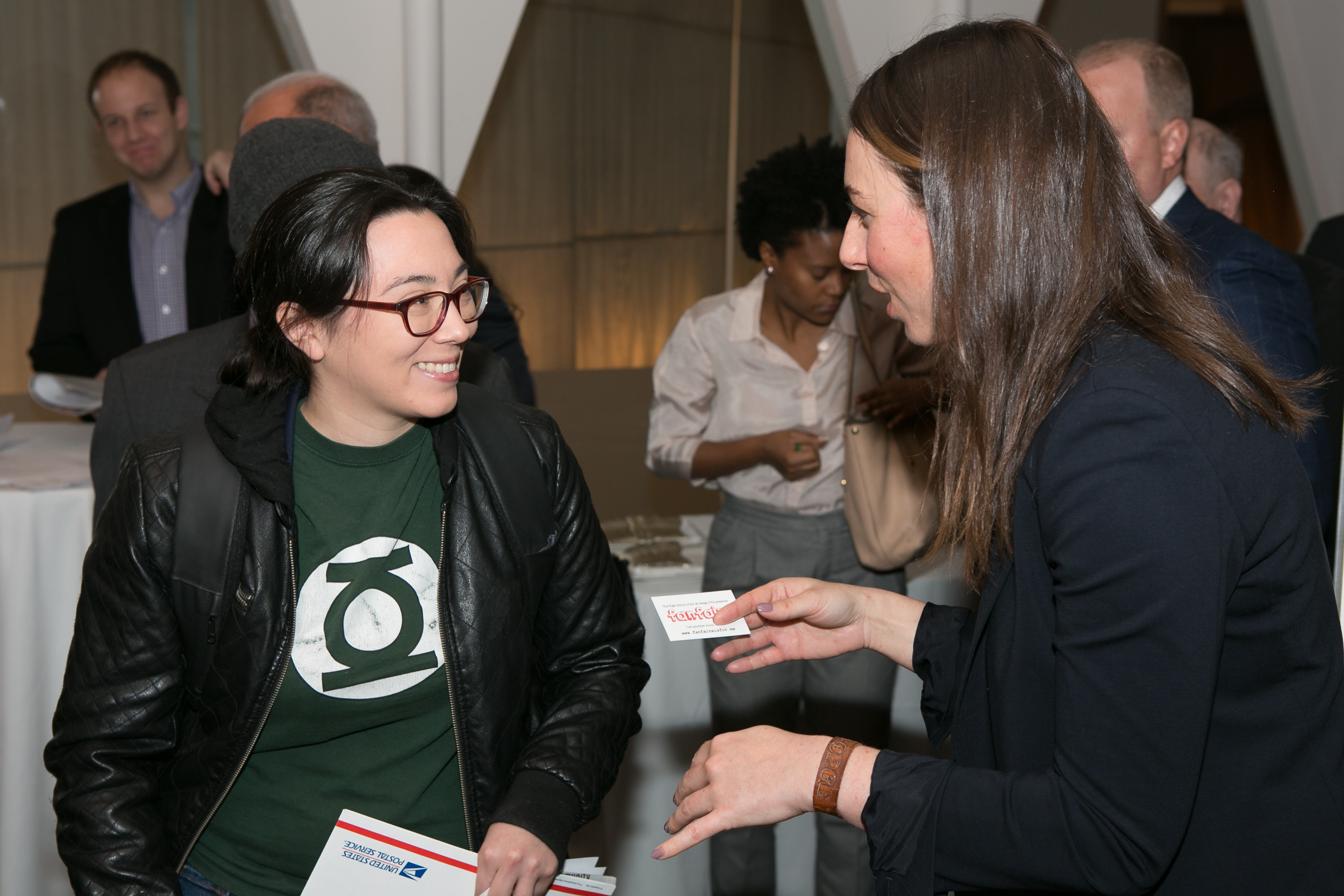 Two people talking at a networking event and exchanging business cards