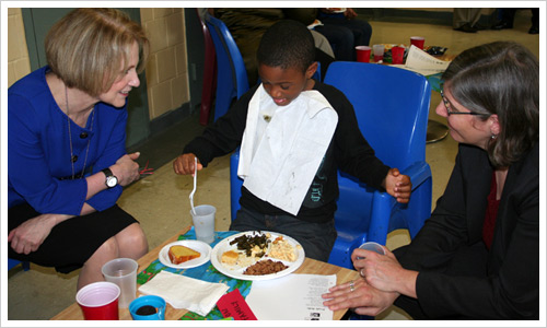 Israel, one of the children visiting with their moms at the holiday party, has the attention of DOC Commissioner Shriro, left, and ACS Deputy Commissioner Liz Roberts.