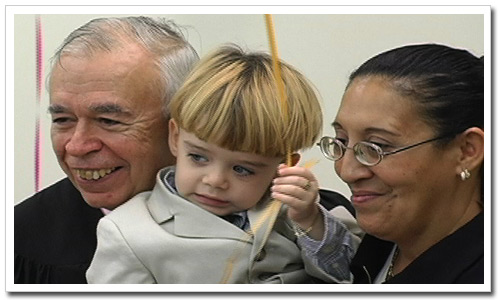 The newest member of the Ascencio Family, Tyler, poses with his mom Lourdes and Family Court Judge Guy de Phillips at their adoption formalization ceremony in Queens last November.