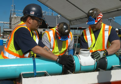 The Bowery Boys team working on the Collections challenge by fixing a broken pipe and replacing it with a new section.
