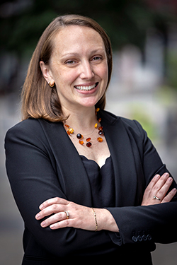 Portrait of N Y C D O T Chief Strategy Officer Julie Bero. She is wearing a black blouse and blazer, crossing her arms and smiling at the camera.