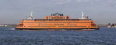 An orange Staten Island Ferry boat cruises in the New York Harbor.