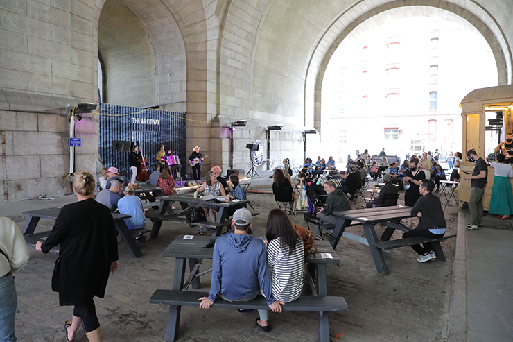 People listen to music and eat food at DUMBO Plaza