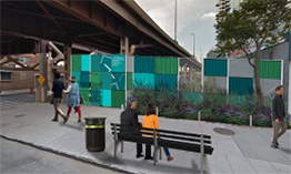 A rendering of “El-Fence”, colorful blocks of green and gray decorate a fence along a sidewalk brightening the space below an elevated roadway.