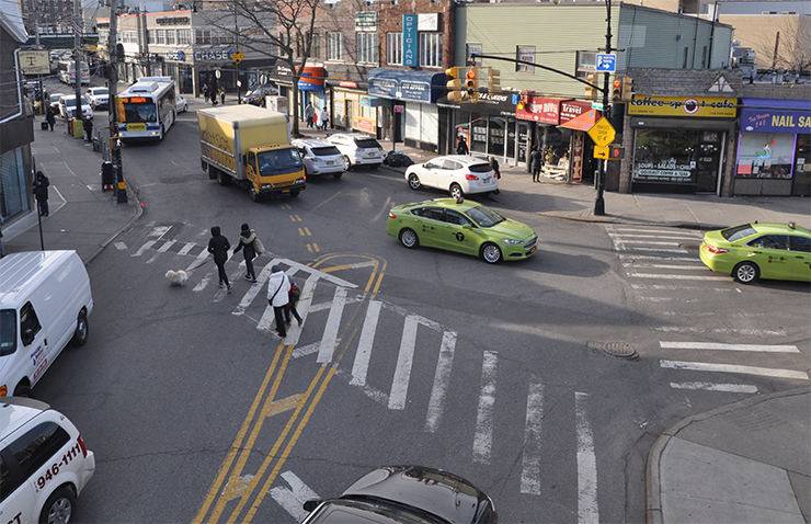Sheepshead Bay Road and Jerome Avenue, before conditions. Pedestrians cross the street as cars maneuver through the intersection.