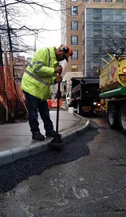 Team member from DOT’s SIM Division tamping asphalt