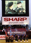 D.S.N.Y. Emerald Society Pipe and Drum Band joins with Honor Guard in center field while jumbotron captures action
