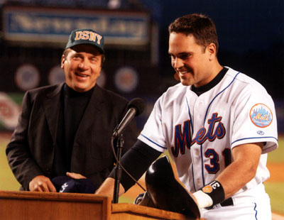 Hall of famer Johnnie Bench shows off his favorite team cap (D.S.N.Y.) while greeting future hall of famer Mike Piazza before the game