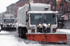 Collection trucks plowing city street