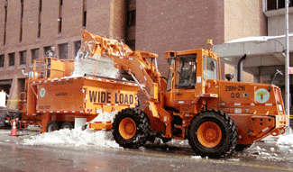 A front-end loader dumping snow into a snow melter