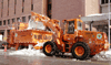 A front-end loader dumping snow into a snow melter