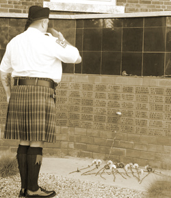 (Left) EMS Lt. Robert White, a member of the EMS Pipes and Drums Band, salutes the 9/11 Memorial at the EMS Academy in Fort Totten.