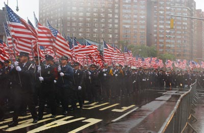 A sea of Firefighters carry American Flags.