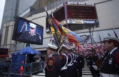 Firefighters from various cities stand in formation in front of Madison Square Garden and watch the Memorial ceremony on one of the many jumbotron screens that were set up outside.
