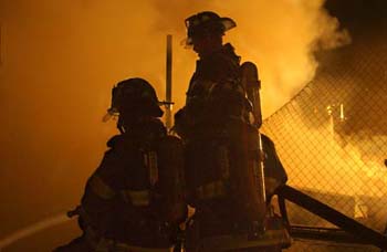 Firefighters battle the blaze from an adjoining roof.