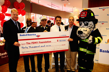 Bank of America presents $40,000 check to the FDNY Foundation. (L to R) NFL analyst Boomer Esiason, Bank of America Banking Center Manager Edwin Warren, Assistant Chief James Esposito, Captain Brian Smith of Squad 18, Bank of America Northeast Region Executive Jeff Barker and FDNY Fire Safety mascot Hot Dog.