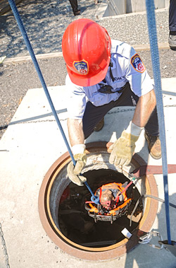 Firefighter James Lopez (in the manhole) helps Lt. Sean Parker remove the 'victim' during a simulated confined space rescue.
