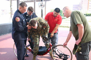 Members of the VFW Post and Zac Briseno (red shirt), who also was wounded by an AED in Iraq, help Matt Bradford onto his new hand-crank bicycle.