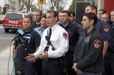 Deputy Chief James DiDomenico tells reporters about the rescue of four civilians from an early morning fire in Queens along with Firefighters Jim Stewart (front left), Anthony Sodano (front right) and Stephen King (second row, far right).