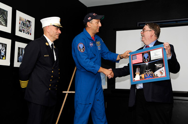 Astronaut Michael J. Massimino (center) presents NYC Fire Museum President of the Board of Trustees John Bower (right) and Chief of Department Salvatore Cassano with a flag and a NASA patch that was flown on the Space Shuttle Atlantis in honor of the 343 members of the FDNY who were killed on Sept. 11, 2001.