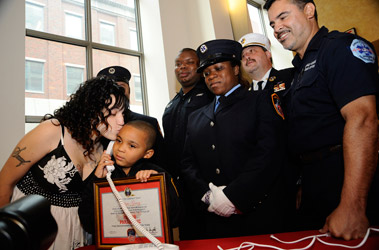 Jennifer Garay gives a kiss to her son, Tahlique, who, at just 5-years-old, called 9-1-1 and saved his mom's life when she became unresponsive in their home on Aug. 5. (L to R) EMT Emilio Navedo (behind Ms. Garay), Paramedic Antaeus Waller, EMT Rose-Marie Cameron, EMS DC Stephen Lincke and Paramedic William Gonzalez.