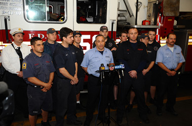Members of Engine 45/Ladder 58 watch as Capt. Joseph Principio tells the media how the company saved a 15-year-old and her grandmother from a fire in the Bronx. Firefighters Scott Mooney (left of the Captain) and Duane Davis (right of the Captain) participated in the rescue.