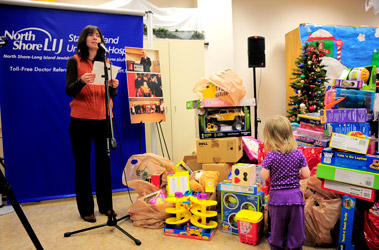 Diane Spallanzani, Lt. Robert Ryan’s sister, addresses the crowd as a little girl surveys the toys.