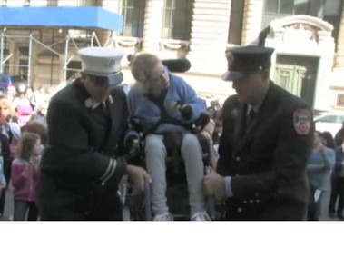 Two FDNY firefighters help carry a girl up the steps of the Tweed Courthouse during the Blue Sky Girls 2011 event.