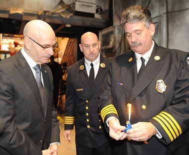 Fire Commissioner Salvatore Cassano (left) and Chief Fire Marshal Robert Byrnes (center) watch as Bryant Stevens from the Office of Fire Prevention and Control demonstrates one of the novelty lighters, which was shaped like a smiling, waving blue bear.