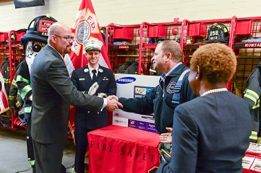 FDNY Deputy Commissioner John Benanti and DCAS Commissioner Edna Wells Handy congratulate members of the firehouse after the ceremony, including Capt. Michael Barvels (white hat).
