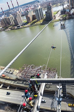 A firefighter transverses over the East River to reach the car during a Roosevelt Island Tramway drill.
