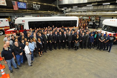 FDNY officials, World Police and Fire Games officials and members of the FDNY Fleet Maintenance stand in front of one of the donated vehicles.