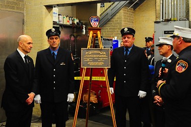 The centennial plaque is blessed on the firehouse’s apparatus floor.