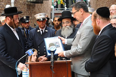 Fire Commissioner Daniel Nigro reads one of the plaques presented to the firefighters who rescued the boy.