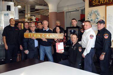 Members of Marine 6 with the Kane family. They are holding the sideboard, portrait of Kevin Kane and framed poem.