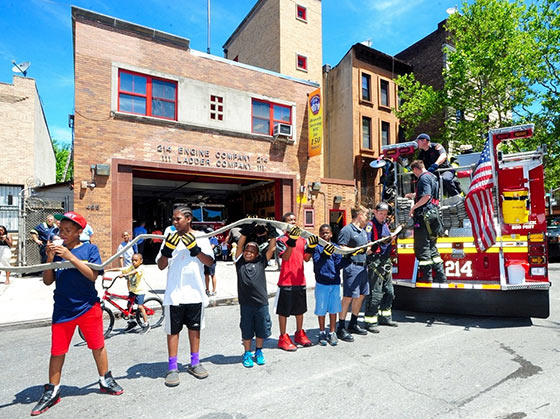 Members of Engine Company 214 and helpers return the hose to the fire engine