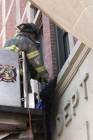 Firefighter Matthew Roberts from Engine 249 and Firefighter Frank Valerio from Ladder 113 hang bunting on the facade of their firehouse in memory of Lt. John Martinson on January 4.
