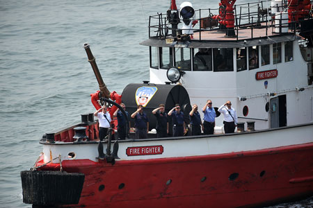 The crew of the Firefighter fireboat stands at attention as the vessel is blessed by FDNY Chaplains Monsignor John Delendick and Reverend Stephen Harding.