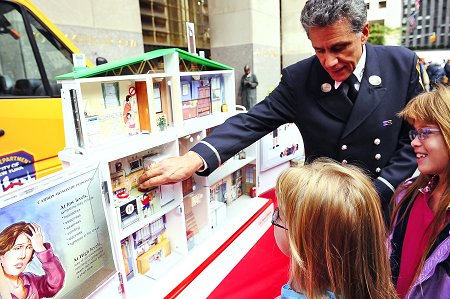 Director of the FDNY Fire Safety Education Unit Lt. Anthony Mancuso shows children how to keep their homes fire safe using the unit's interactive Hazard House.