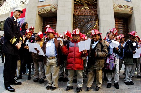 Chief of Department Salvatore Cassano swears in children from Achievement First Crown Heights Elementary as honorary firefighters and paramedics.