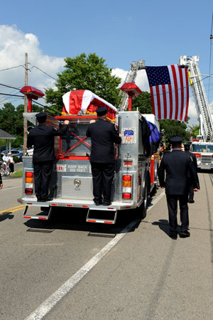 Firefighters from Engine 221 and Ladder 104 escort the casket during the funeral procession.