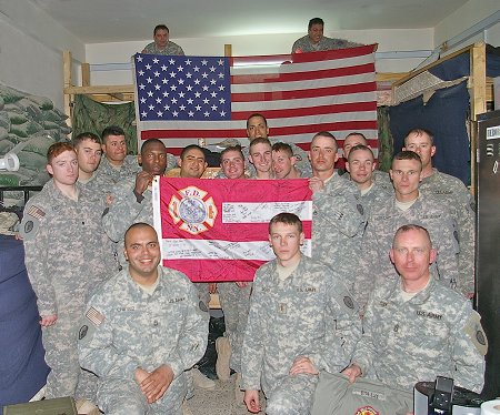 Members of the U.S. Army with the FDNY flag signed by firefighters from Engine 34/Ladder 21 and the American flag that was flown over the firehouse on Sept. 11, 2001.
