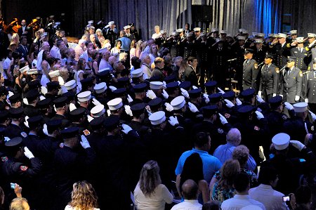 The large crowd at the Intrepid Air, Sea and Space Museum stand as the FDNY Singers sing the National Anthem.