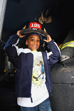 Young girl tries on fire helmet during a Operation Side walk during a street fair.
