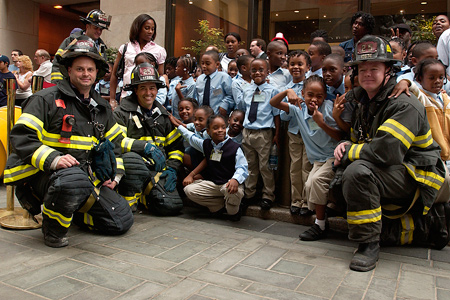 Firefighters pose with schoolchildren during outdoor event at Rockefeller Center.