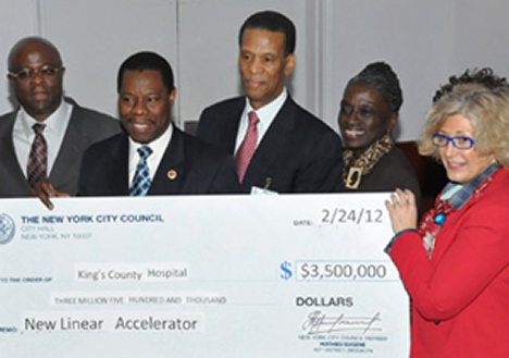 Council Member Mathieu Eugene (center) presents a $3.5M check to Kings County Hospital SVP George Proctor and Acting Executive Director Roslyn Weinstein