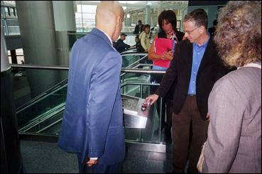 Roseanne Caruana, Director, DOT (red folder) looks on as Steven Landau, Touch Graphics; demonstrates kiosk