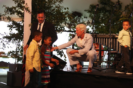 Deputy Mayor Gibbs helps Rajib’s three children up onto the stage to join their father