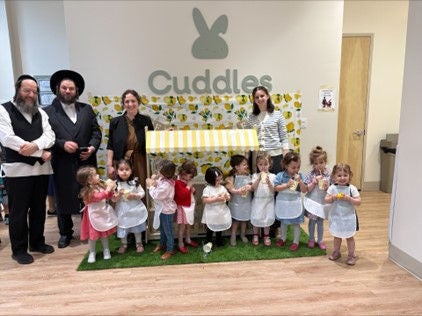 Children and adults standing in front of a logo for Cuddles Center