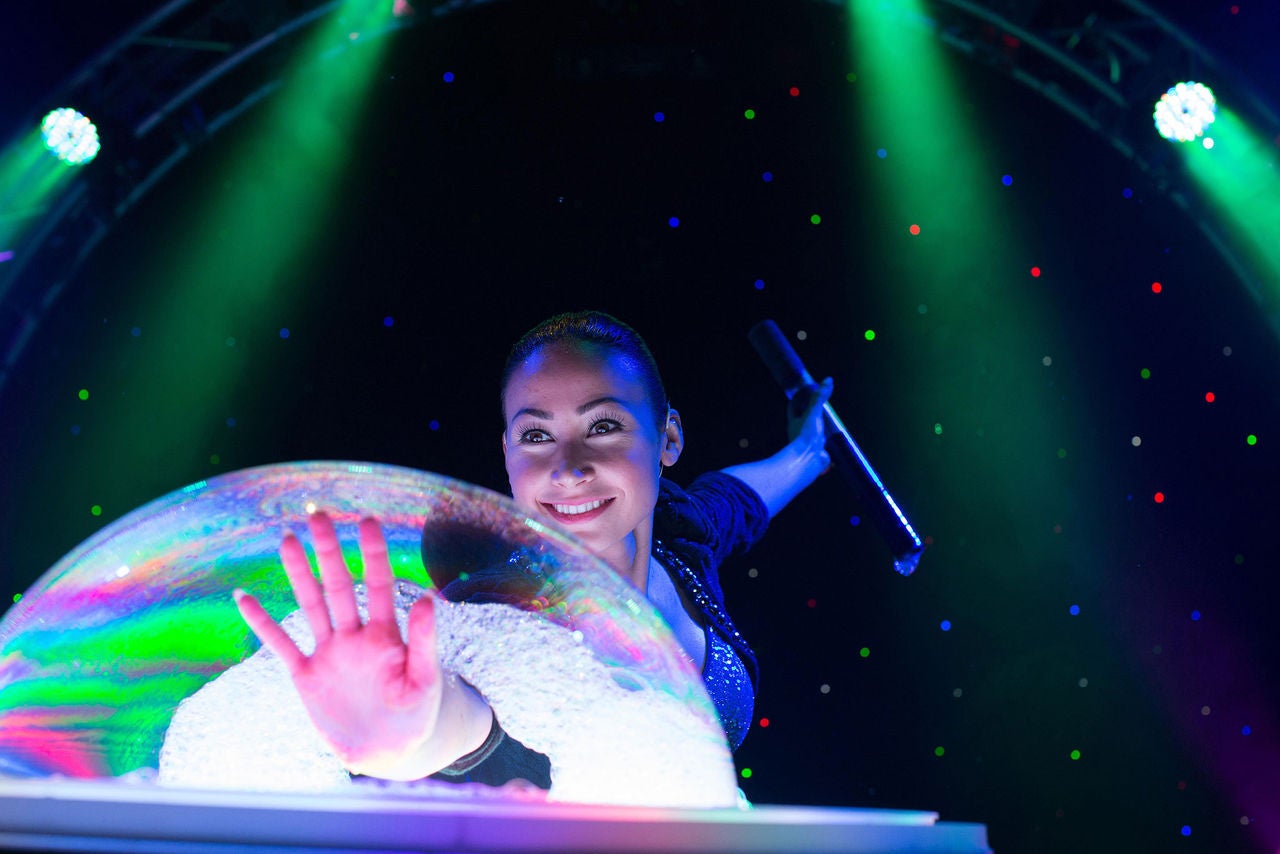 Photo of woman with hand in a soap bubble at a off-broadway show